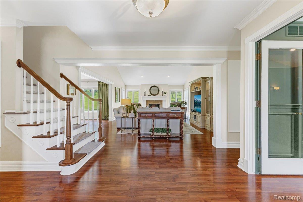 69075 Brookhill Drive Romeo, MI 48065 - Photo 4 of 28 Hardwood flooring throughout the entry, a detailed staircase with wood handrails and carpeted treads, and extensive crown molding