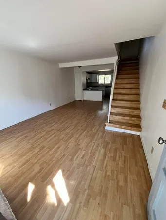 a view of empty room with stairs and wooden floor