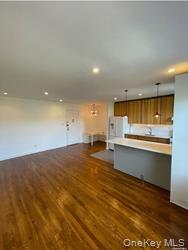 102-12 65th Avenue, Unit 43C Queens, NY 11375 - Photo 10 of 15 a large kitchen with stainless steel appliances a large counter top and a wooden floor