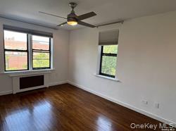 102-12 65th Avenue, Unit 43C Queens, NY 11375 - Photo 11 of 15 an empty room with wooden floor fan and windows