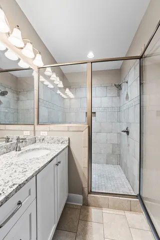 a bathroom with a granite countertop shower a mirror and a sink