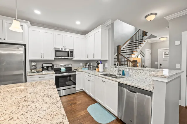 a kitchen with stainless steel appliances granite countertop a sink stove refrigerator and cabinets