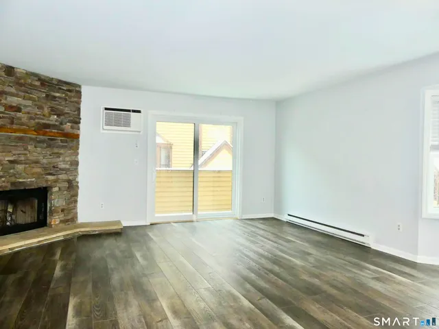 an empty room with wooden floor fireplace and windows