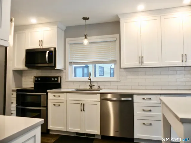 a kitchen with granite countertop a sink stainless steel appliances and cabinets