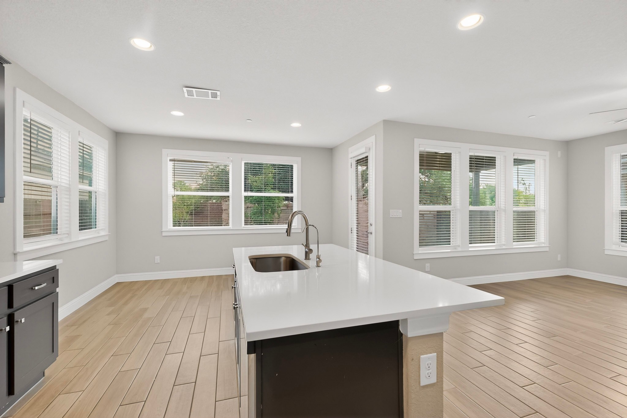 2605 Sam Bass Road, Unit 9 Round Rock, TX 78681 - Photo 17 of 38 A contemporary kitchen island with a gleaming white countertop and stainless steel sink anchors this open-concept living area.
