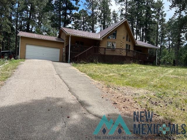 27 Golf Drive Rociada, NM 87742 - Photo 8 of 10 View of front facade with a deck, driveway, a front yard, a metal roof, and an attached garage