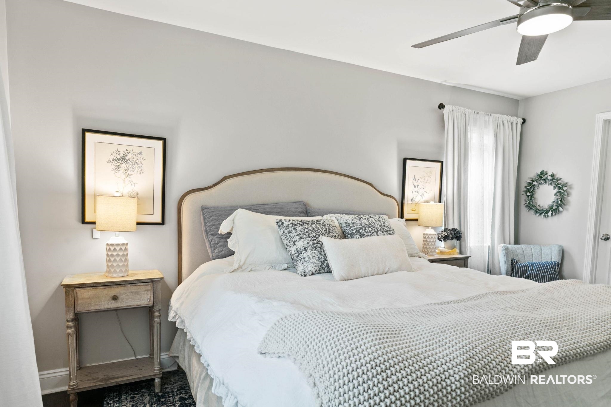 22810 High Ridge Road Fairhope, AL 36532 - Photo 34 of 78 Bedroom featuring a curved upholstered headboard, a ceiling fan with integrated lighting, wood-finish flooring, and light gray wall paint