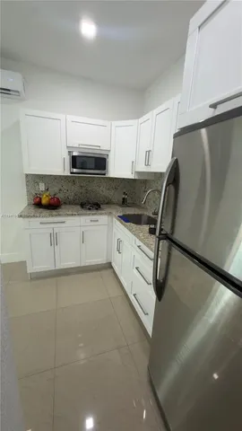 a kitchen with granite countertop a sink a stove a refrigerator and cabinets