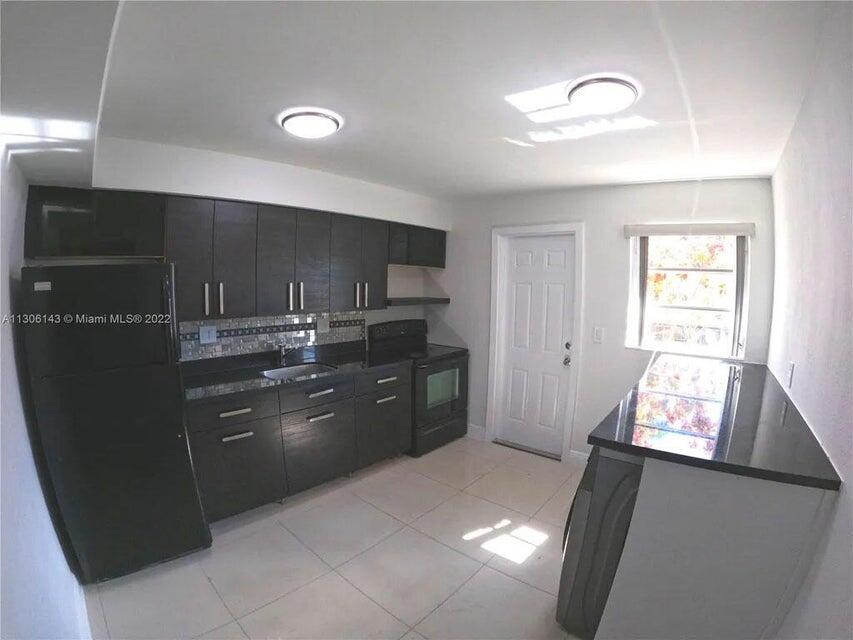 538 Southwest 7th Street Hallandale Beach, FL 33009 - Photo 22 of 35 a kitchen with granite countertop a refrigerator and cabinets