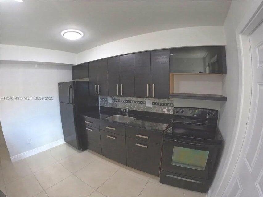 538 Southwest 7th Street Hallandale Beach, FL 33009 - Photo 23 of 35 a kitchen with stainless steel appliances wooden cabinets and a sink