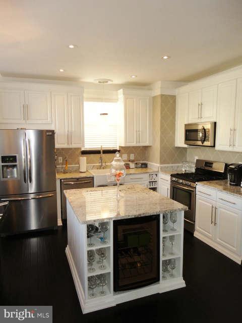 43396 Edgewater Street Chantilly, VA 20152 - Photo 4 of 16 a kitchen with stainless steel appliances granite countertop a stove a refrigerator a sink a stove with white cabinets