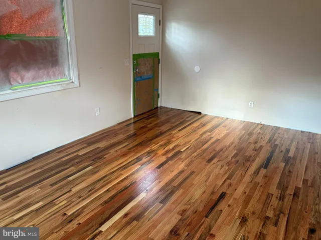 a view of empty room with window and wooden floor