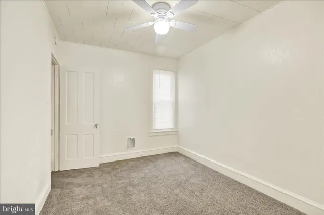 an empty room with a chandelier fan and windows