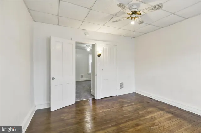 an empty room with wooden floor and ceiling fan