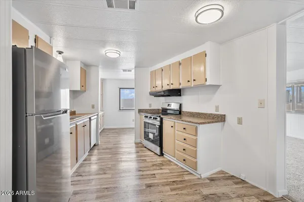 a kitchen with stainless steel appliances granite countertop a refrigerator a stove and white cabinets with wooden floors