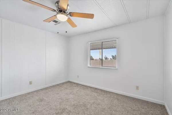an empty room with a window and a fan