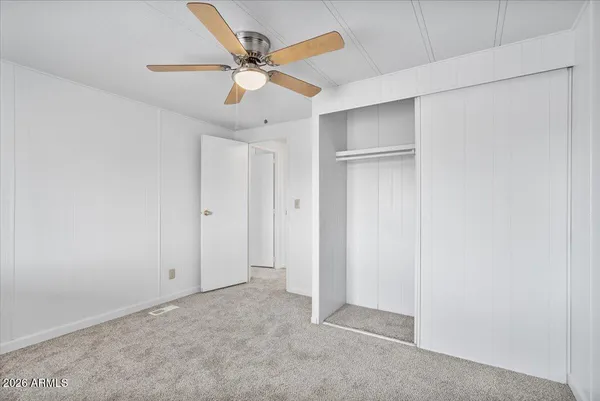 an empty room with closet and fan