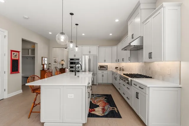 a kitchen with stainless steel appliances white cabinets and wooden floor
