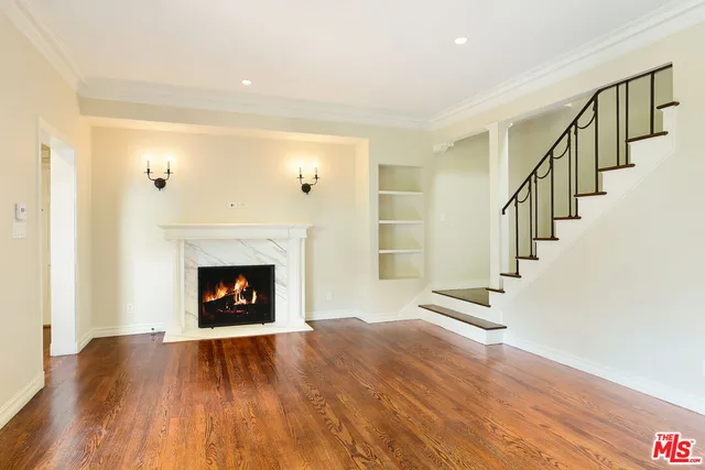 a view of an empty room with wooden floor fireplace and a window