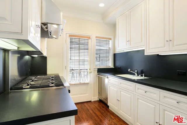 a kitchen with a sink a stove and white cabinets