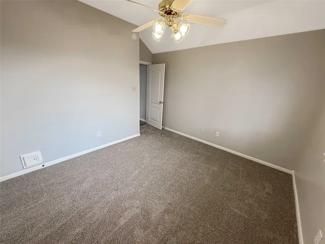 an empty room with a chandelier fan and windows