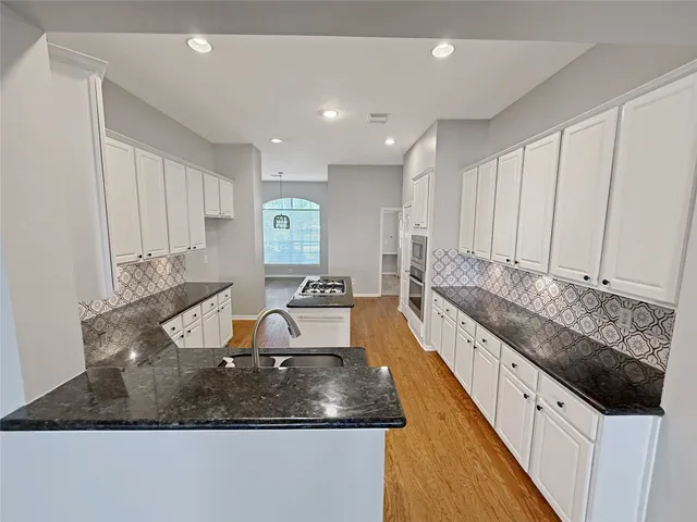 a large kitchen with kitchen island granite countertop a sink and white cabinets