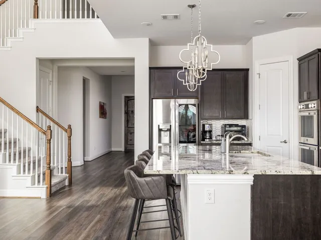 a kitchen with stainless steel appliances granite countertop a sink dishwasher and a dining table with wooden floor