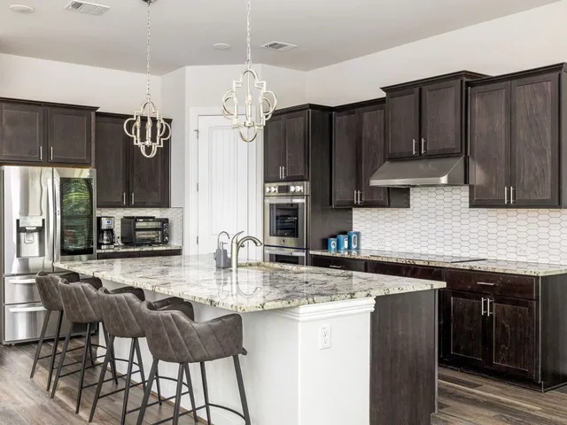 a kitchen with granite countertop a sink cabinets and stainless steel appliances