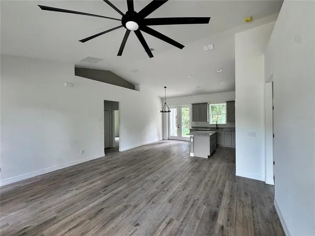 a kitchen with a sink wooden floor and a view of living room