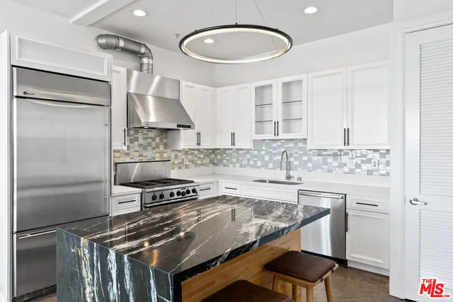 a kitchen with stainless steel appliances a stove and white cabinets
