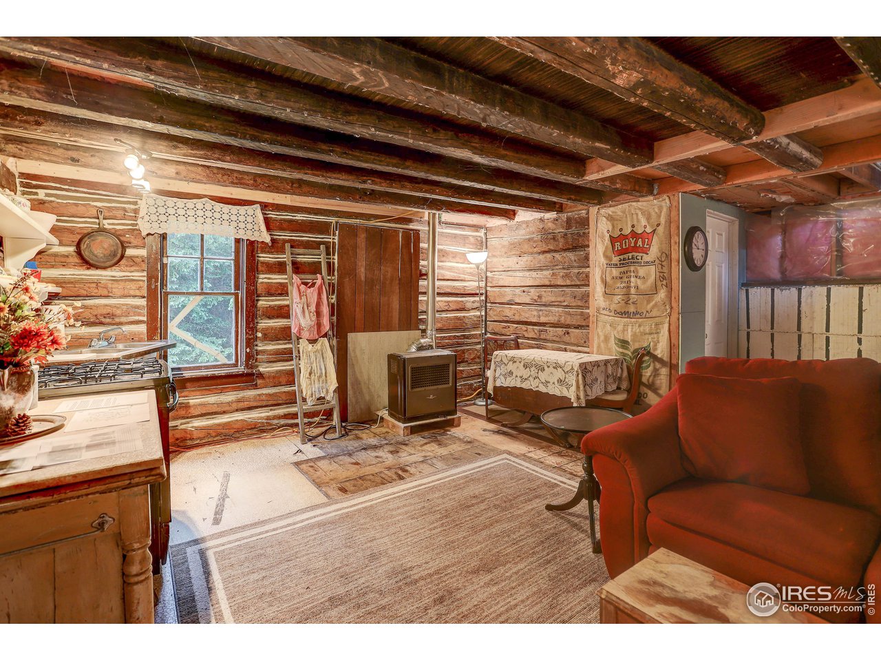 5672 Apex Valley Road Idaho Springs, CO 80452 - Photo 11 of 23 Living/kitchen area w/original log wall, hand-hewn rafters and wood flooring