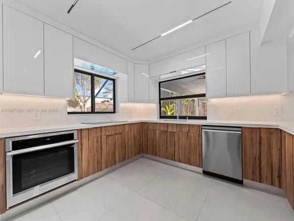a view of kitchen with refrigerator and white cabinets