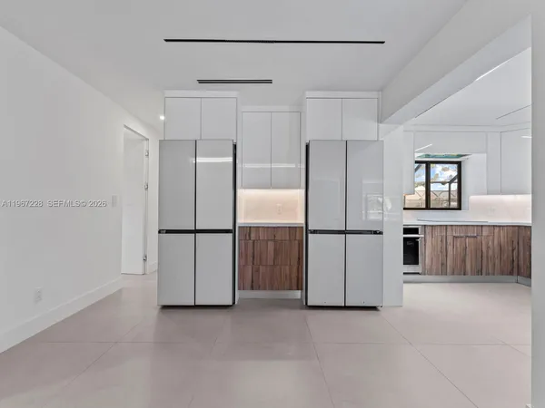 a view of a kitchen with refrigerator and white cabinets