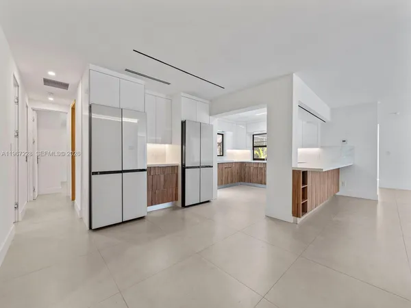 a view of a refrigerator in kitchen and an empty room