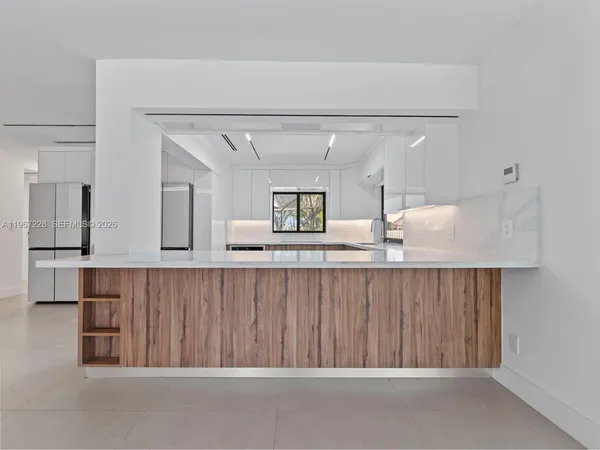 a view of an empty room with window and a kitchen