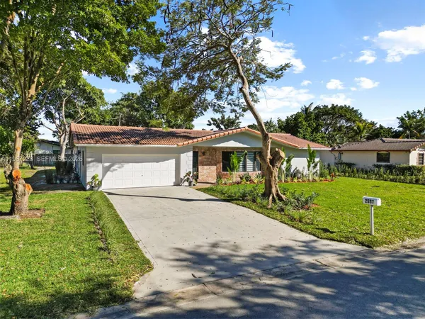 a view of a house with a big yard plants and large trees