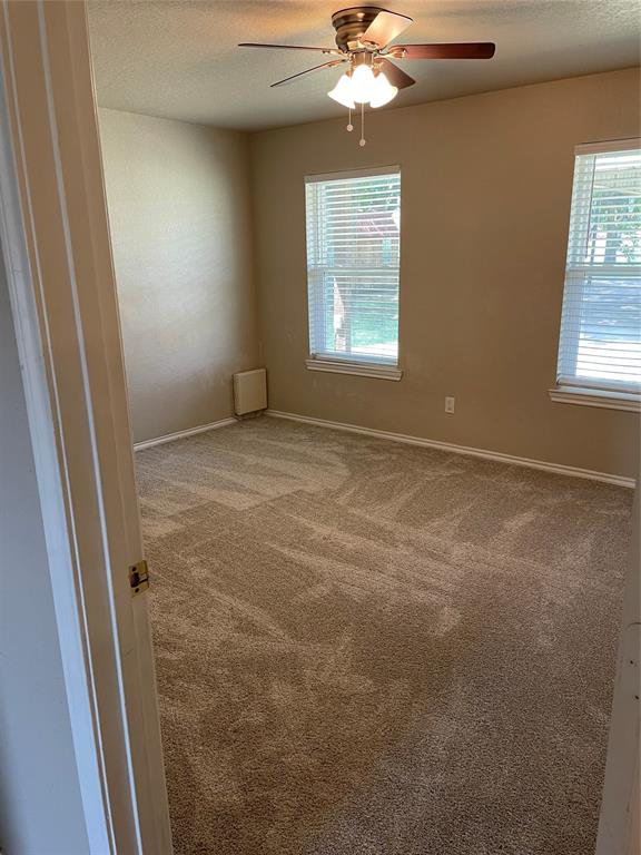 111 Quail Drive Springtown, TX 76082 - Photo 12 of 22 en empty room with windows and chandelier fan