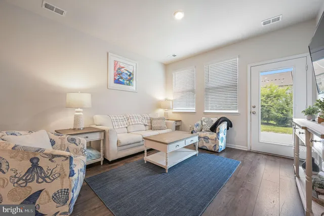 a living room with furniture a large window and wooden floor