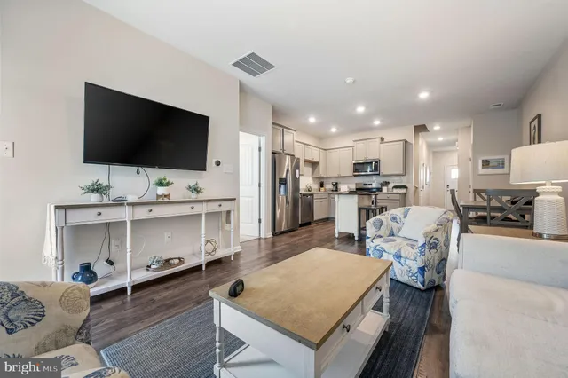 a living room with stainless steel appliances furniture and a flat screen tv