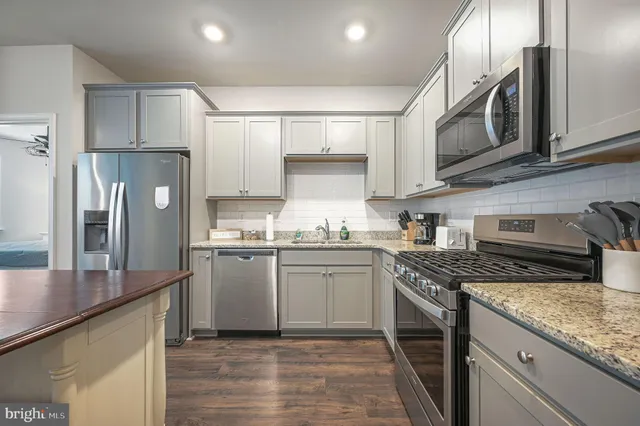 a kitchen with stainless steel appliances granite countertop a sink a stove a refrigerator and island