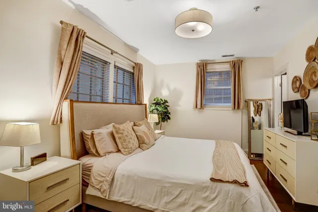 a bedroom with a bed and a flat tv screen on dresser