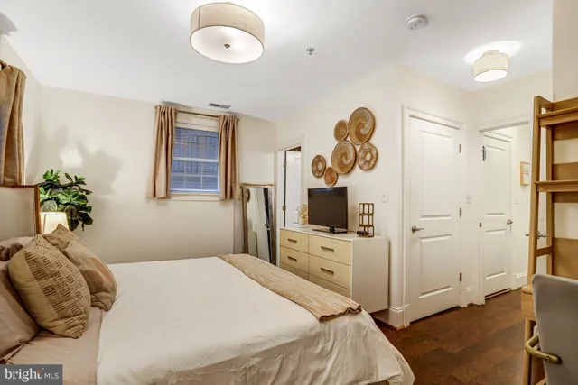 a bedroom with a bed and a flat tv screen on dresser