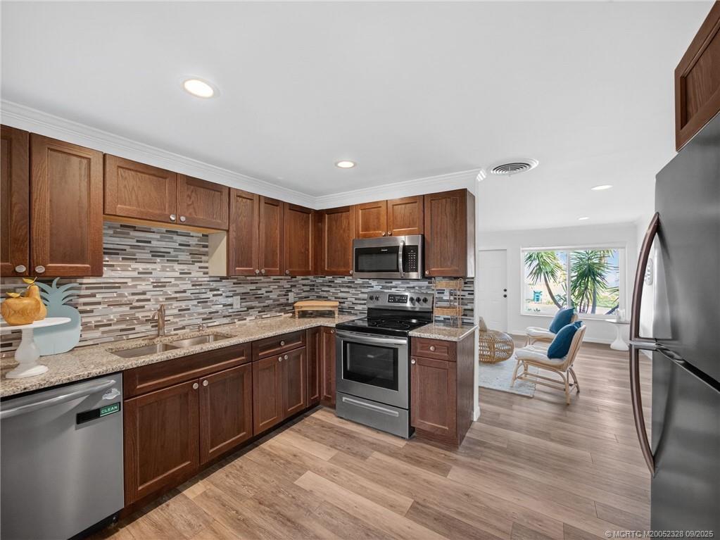 2346 Northeast Rustic Place Jensen Beach, FL 34957 - Photo 6 of 18 a kitchen with stainless steel appliances granite countertop a stove top oven a sink dishwasher a refrigerator and cabinets with wooden floor