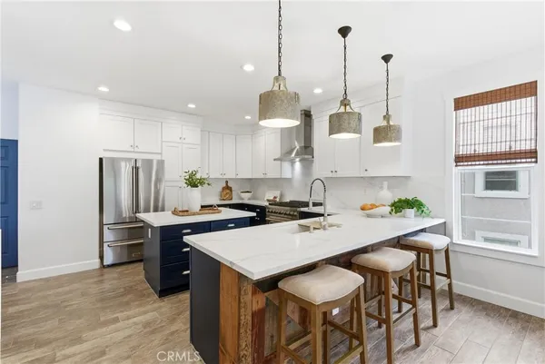 a kitchen with stainless steel appliances a stove a sink a dining table and chairs with wooden floor