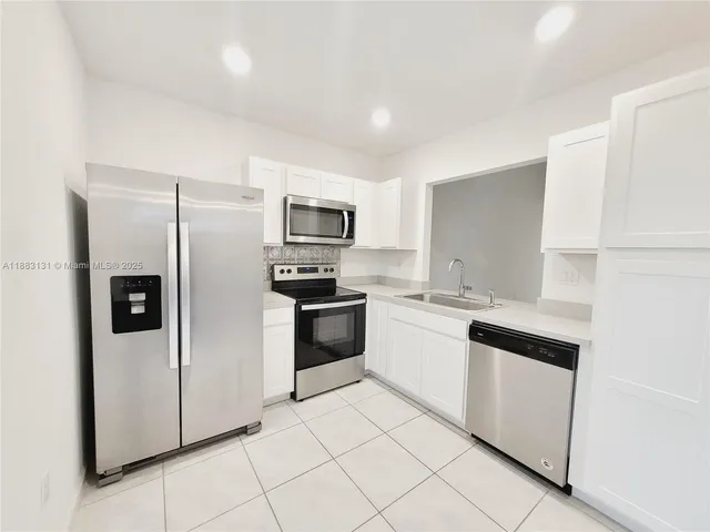 a kitchen with white cabinets and stainless steel appliances