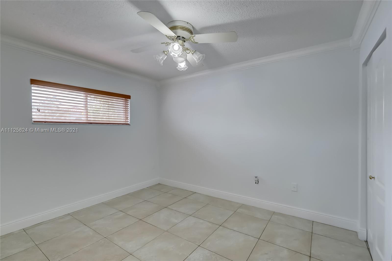 6858 West 30th Lane Hialeah, FL 33018 - Photo 13 of 37 an empty room with a chandelier fan