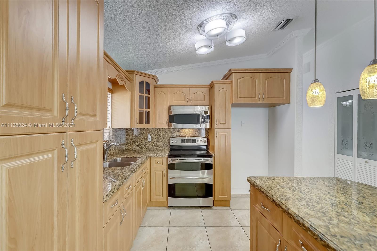 6858 West 30th Lane Hialeah, FL 33018 - Photo 19 of 37 a kitchen with stainless steel appliances granite countertop a stove and cabinets