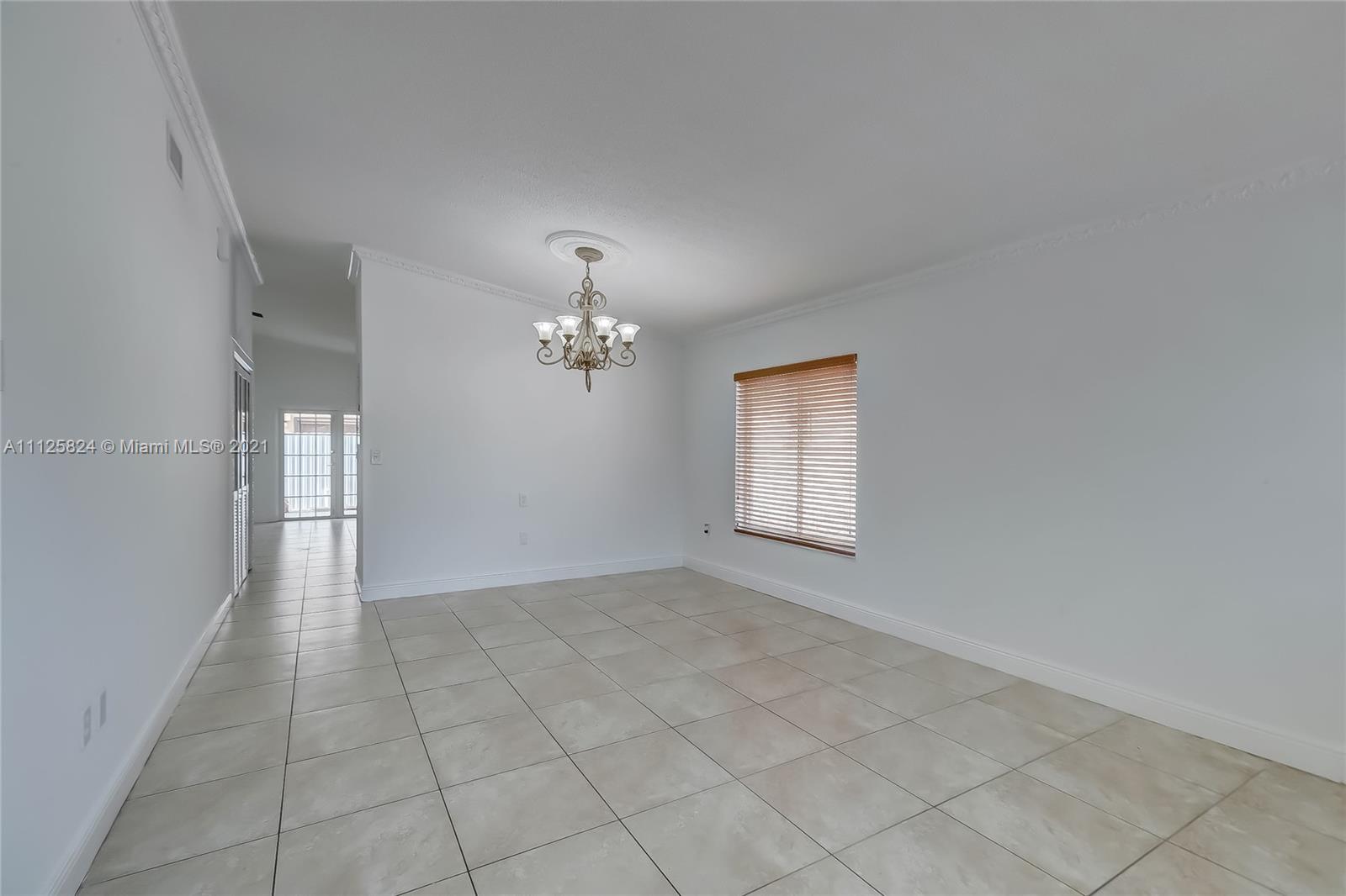 6858 West 30th Lane Hialeah, FL 33018 - Photo 5 of 37 an empty room with chandelier fan and windows