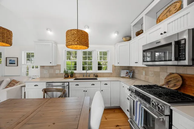 a kitchen with stainless steel appliances granite countertop a sink a stove and a granite counter tops with white cabinets