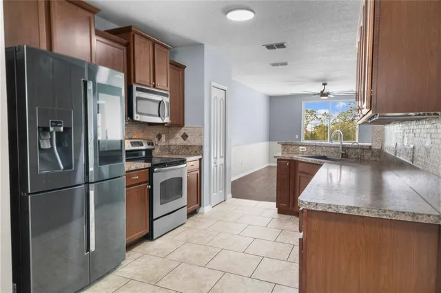 a kitchen with stainless steel appliances granite countertop a refrigerator a stove and a sink